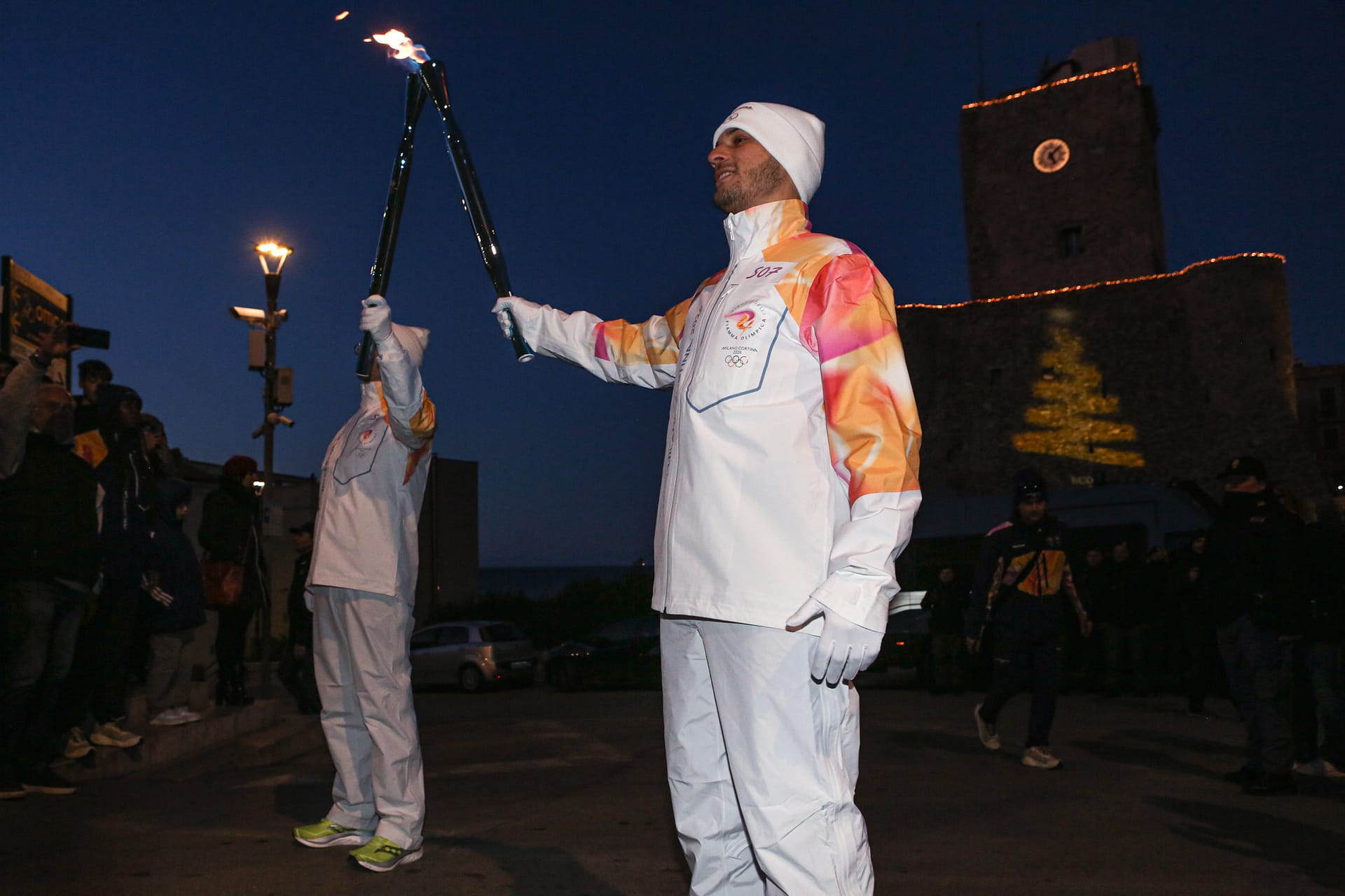 Torchbearers hold the Olympic torch during the exchange of the Olympic flame at the Milano Cortina 2026 Olympic Torch Relay in Termoli, Italy, on January 1, 2026.